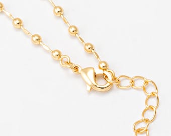 May include: A gold-colored necklace with a ball chain design. The necklace features a lobster clasp and an extender chain for adjustable sizing. The jewelry is displayed against a white background.