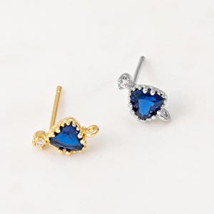 May include: Two pairs of heart-shaped earrings with blue gemstones and clear accents. One pair is gold-toned and the other is silver-toned.