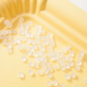 Peut inclure: Une assiette en papier jaune remplie de petites perles en plastique transparentes.