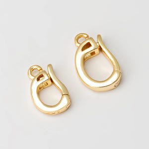 以下が含まれることがあります： ジュエリー作りのための2つの金色の金属製留め具。留め具は楕円形で、バネ式の留め具です。