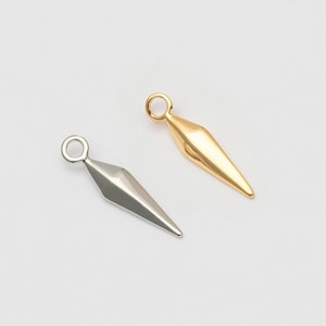 Peut inclure: Deux breloques métalliques, une argentée et une dorée, chacune avec un design géométrique pointu et une petite boucle en haut. Ces breloques sont idéales pour la création de bijoux, comme des boucles d'oreilles ou des pendentifs.