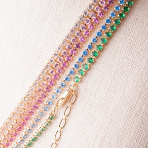 May include: A multi-colored chain necklace with a gold clasp. The chain is made of small, round stones in shades of pink, blue, and green.