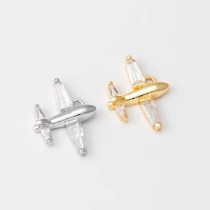 May include: Two airplane charms, one silver and one gold, with clear crystal accents.