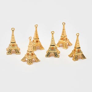 May include: Seven gold Eiffel Tower charms, each with intricate details, ideal for jewellery making or crafting projects.