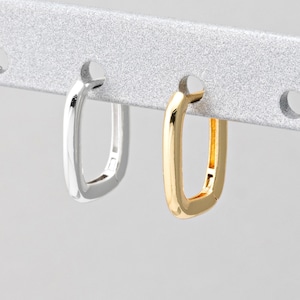 May include: Two pairs of small, square hoop earrings. One pair is silver and the other is gold.