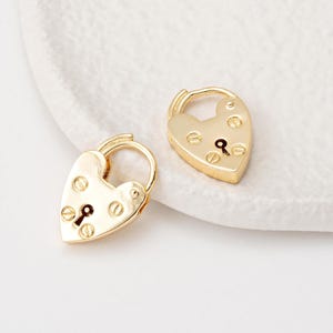 Puede incluir: Un par de pendientes de corazón de oro. Las cerraduras tienen una cerradura y pequeños detalles decorativos.