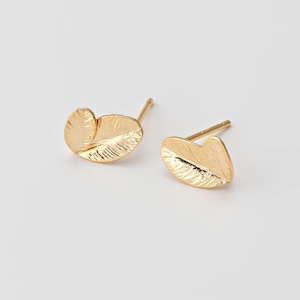 May include: A pair of gold-colored stud earrings. Each earring is shaped like a stylized leaf with detailed veining. The earrings have a post and backing for secure wear, and are set against a plain white background.
