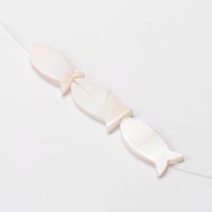 Può includere: Una fila di perline a forma di pesce, di colore bianco crema con una lucentezza iridescente. I pesci hanno un design semplice con una coda e un piccolo foro per infilare. Le perline sono infilate su un cordino trasparente.