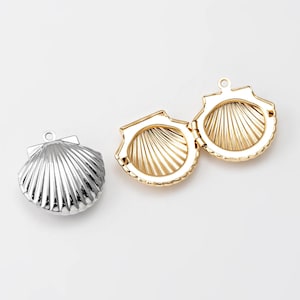 May include: Two seashell-shaped locket pendants, one silver and one gold, open to reveal an empty interior. The lockets are detailed with a ribbed texture.