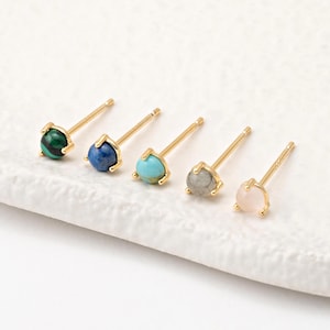 May include: Five pairs of gold stud earrings with different coloured gemstones. The gemstones are malachite, lapis lazuli, turquoise, labradorite, and rose quartz.
