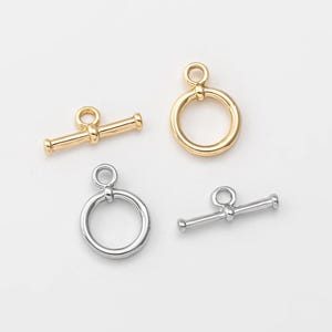以下が含まれることがあります： 金と銀のトグルクラスプの2セット。各セットには、丸いリングと、両端に小さなループが付いたバーが含まれています。