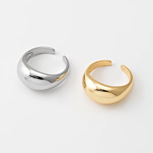 May include: Two simple, modern rings. One is silver and the other is gold. Both rings are smooth and have a rounded shape.