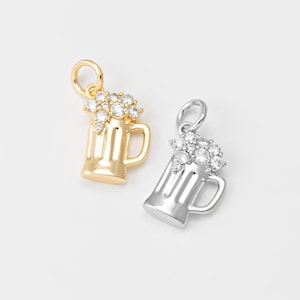 May include: Two beer mug charms, one gold-toned and one silver-toned, each with a handle and a bubbly top of clear crystals. The charms are designed for jewelry making or as decorative elements.