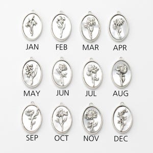 May include: Twelve silver-coloured oval pendants, each with a different floral design and a month abbreviation. The pendants are arranged in a grid, representing each month from January to December. The floral details are intricately designed.
