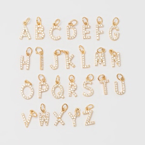 以下が含まれることがあります： クリアな輝くラインストーンが埋め込まれた、26個のゴールドトーンのアルファベットチャームのセットです。