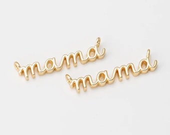 May include: Two gold-colored charms in a cursive font that spell out "mama". The charms are in a script style, with a loop at the end of the "a" letters. The background is plain white.