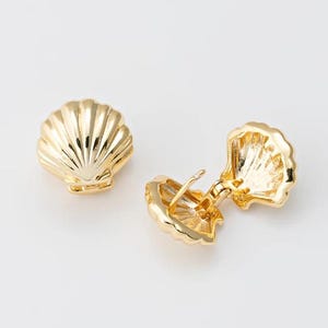 May include: A pair of gold-tone seashell shaped clip-on earrings.
