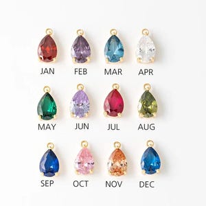 May include: Twelve teardrop-shaped charms with different coloured crystals, each charm is labelled with a month of the year, January through December.