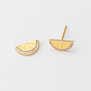 May include: A pair of gold earrings featuring a yellow enamel lemon slice design with clear crystal accents.