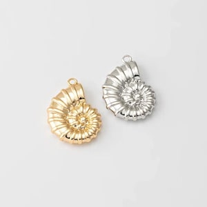 May include: Two gold and silver nautilus shell charms. The charms are detailed and have a spiral design.