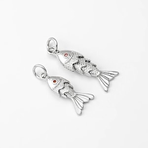May include: Two silver fish charms with red gemstone eyes. The charms are detailed with scales and fins.