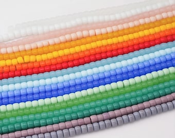 May include: Rows of colorful square beads in a variety of colors, including white, pink, yellow, orange, red, light blue, dark blue, green, and purple. The beads are strung together, creating a rainbow effect. These beads are perfect for jewelry making.