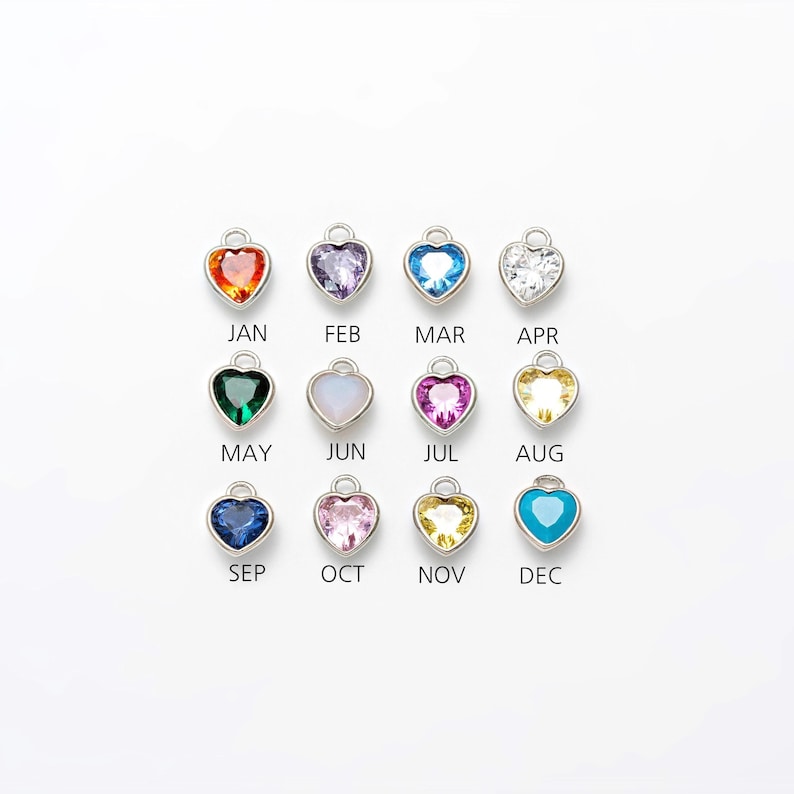 May include: Twelve silver heart-shaped charms with different colored gemstones, representing each month of the year. January is red, February is purple, March is blue, April is clear, May is green, June is white, July is pink, August is yellow, September is blue, October is pink, November is yellow, and December is turquoise.