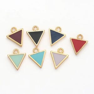 May include: Seven colorful triangle charms with gold-colored edges and a loop for hanging. The triangles are in shades of burgundy, black, navy, red, mint green, turquoise, and lavender. These charms are suitable for jewelry making.