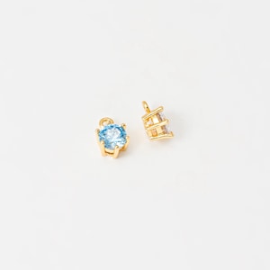 May include: Two gold-tone charms with clear and blue crystal accents. The charms are designed to be added to necklaces, bracelets, or other jewelry.