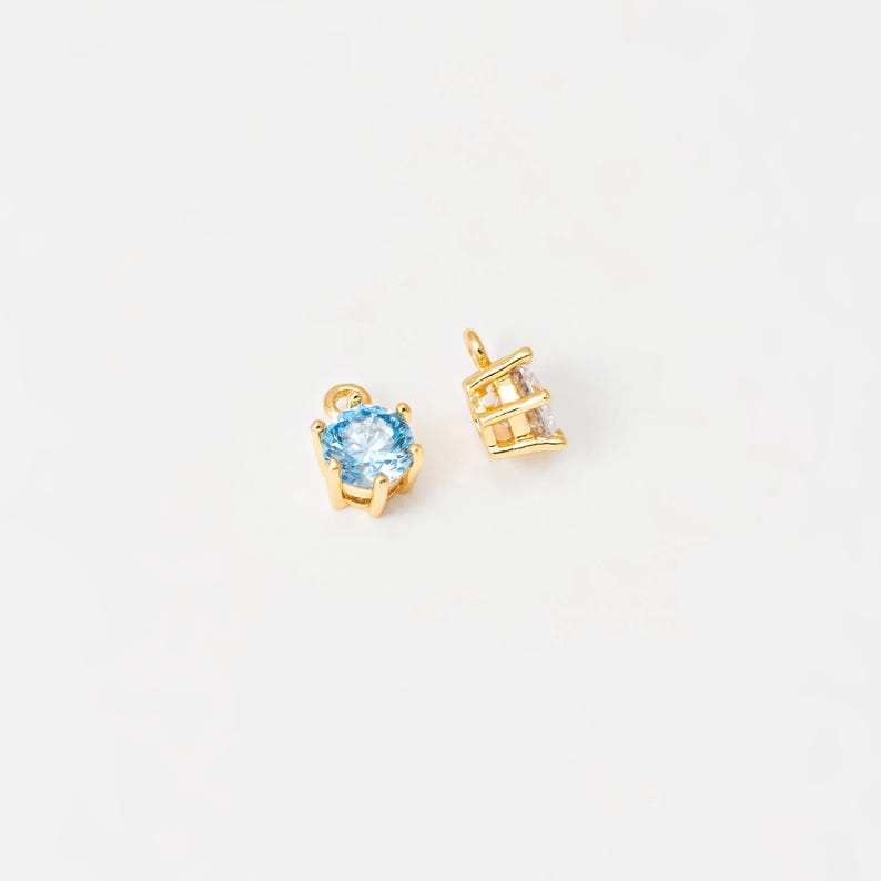 May include: Two gold-tone charms with clear and blue crystal accents. The charms are designed to be added to necklaces, bracelets, or other jewelry.