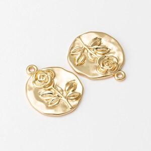 May include: Two gold-tone metal charms featuring a raised rose design. Each charm has a loop for attaching to jewelry or other crafts.