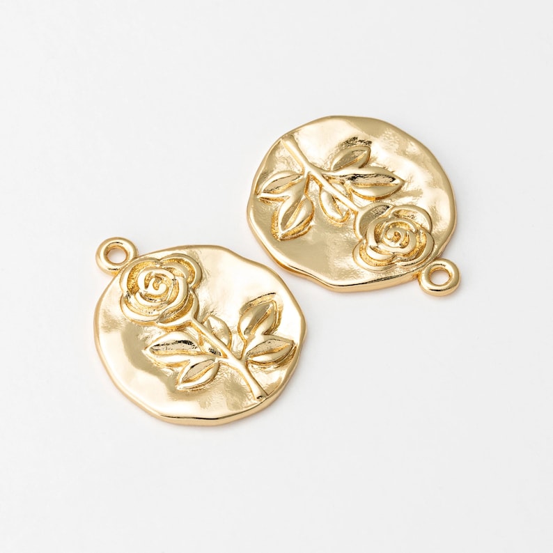 May include: Two gold-tone metal charms featuring a raised rose design. Each charm has a loop for attaching to jewelry or other crafts.