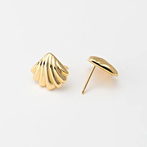 May include: A pair of gold-coloured seashell stud earrings. The earrings are shaped like small, detailed seashells with a post and backing. The earrings are on a white background.