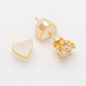 Peut inclure: Une paire de boucles d'oreilles en forme de cœur dorées avec une pierre transparente dans un sertissage en couronne.