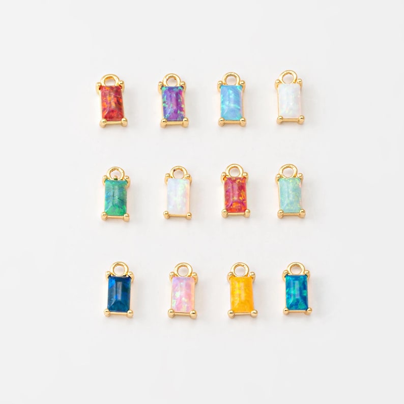 May include: Twelve gold charms with different colored opal stones. Each charm has a loop for attaching to a necklace or bracelet.
