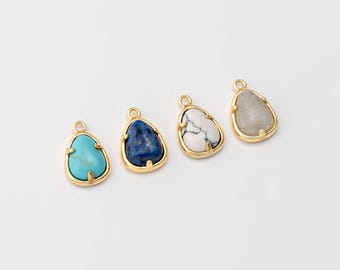 May include: Four gemstone pendants with gold-colored frames. The gemstones are turquoise, dark blue, white with black veining, and light gray. Each pendant has a small loop at the top for attaching to a chain or other jewelry.