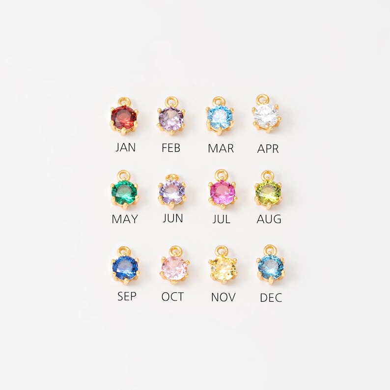 May include: Twelve gold charms with different colored crystals, each representing a month of the year.  January is red, February is purple, March is blue, April is clear, May is green, June is lavender, July is pink, August is green, September is blue, October is pink, November is yellow, and December is blue.