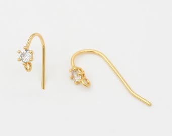 May include: Two gold-colored, hook-style earrings. Each earring features a clear, square-cut gemstone set in a gold-colored metal. The earrings are displayed against a plain white background.