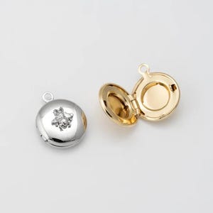 May include: Two round locket pendants, one silver with a bee design and one gold. Both lockets are open to reveal the inside.