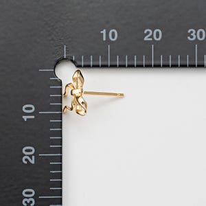 Op de afbeelding: Gouden oorbelletjes in de vorm van een strik. De oorbelletjes zijn klein en delicaat, en zouden een geweldig cadeau zijn voor een speciale gelegenheid.