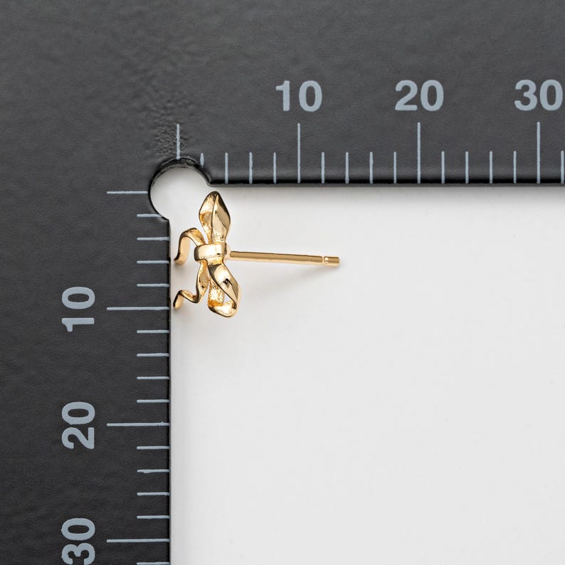 Op de afbeelding: Gouden oorbelletjes in de vorm van een strik. De oorbelletjes zijn klein en delicaat, en zouden een geweldig cadeau zijn voor een speciale gelegenheid.