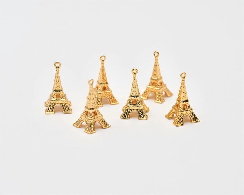 May include: Seven gold Eiffel Tower charms, each with intricate details, ideal for jewellery making or crafting projects.
