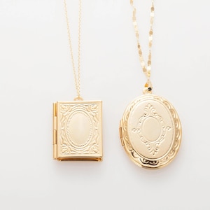 May include: Two gold necklaces with lockets. One locket is a round oval shape with an ornate design. The other locket is a rectangular shape with a simple design.