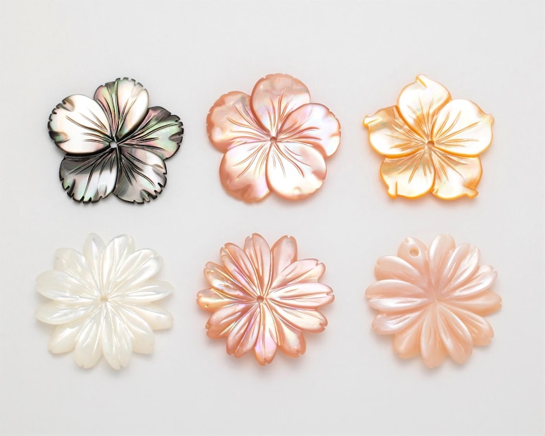 Puede incluir: Seis colgantes con forma de flor de n&aacute;car en varios colores. Los colgantes incluyen una flor negra y plateada, una flor melocot&oacute;n, una flor amarilla, una flor blanca, una flor rosa y una flor naranja claro.