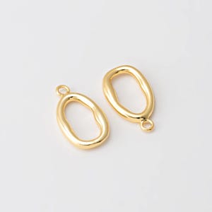 Puede incluir: Dos colgantes de joyer&iacute;a dorados de forma ovalada con un lazo en la parte superior para sujetarlos a una cadena u otro componente de joyer&iacute;a. Los colgantes tienen un acabado liso y pulido y una forma ligeramente irregular.