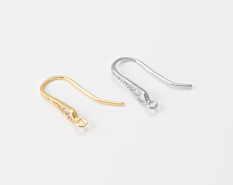 May include: Two earring hooks, one gold-colored and one silver-colored, are displayed against a white background. The hooks are curved with a small loop at the bottom and a decorative section with small, clear stones.