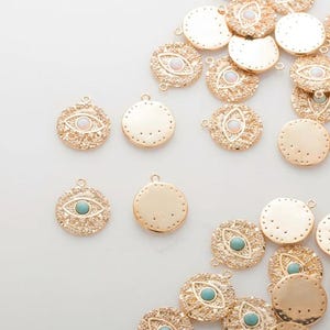 May include: Gold-toned metal charms featuring an eye design. Some charms have a white or turquoise stone in the centre of the eye. The charms have a textured surface and a loop for attaching to jewellery.