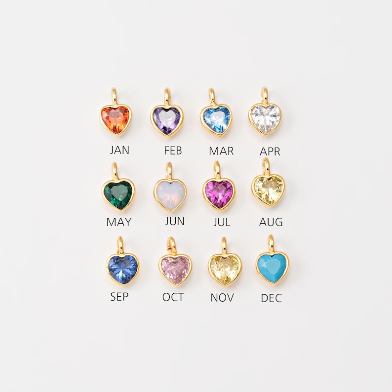 May include: Twelve gold heart charms with different colored gemstones, representing each month of the year. January is orange, February is purple, March is blue, April is white, May is green, June is white, July is pink, August is yellow, September is blue, October is pink, November is yellow, and December is turquoise.