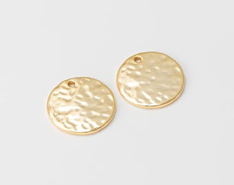 May include: Two gold-colored, hammered-texture round charms with small holes at the top. The charms are on a white background. These jewelry components are ideal for crafting earrings, pendants, or other accessories.