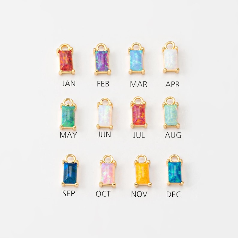 May include: Twelve gold charms with different colored opal stones, each representing a month of the year. The charms are labeled with the months: January, February, March, April, May, June, July, August, September, October, November, and December.